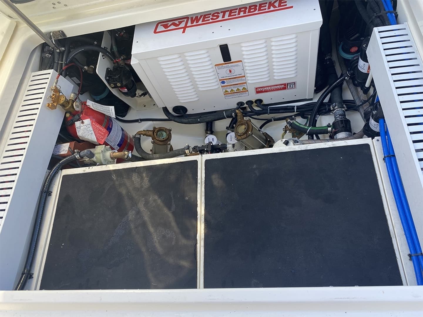 Engine compartment of 2023 Boston Whaler 350 Realm with generator and fire extinguisher.